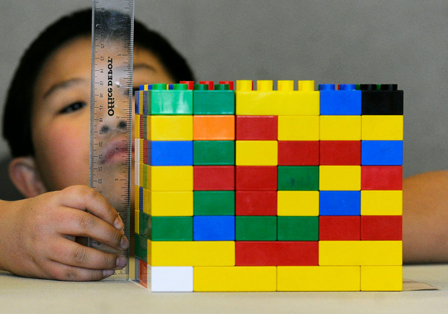 boy measuring LEGO building with a clear ruler