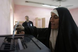 A woman drops a ballot into a ballot box