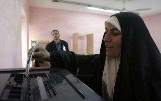 A woman drops a ballot into a ballot box