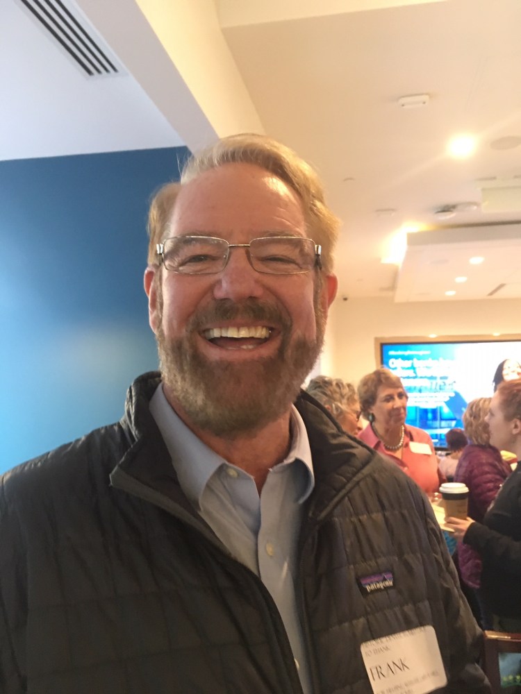 a man wearing glasses and smiling at the camera