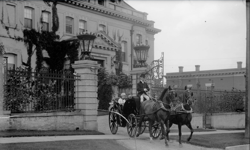 a person riding a horse drawn carriage on a city street