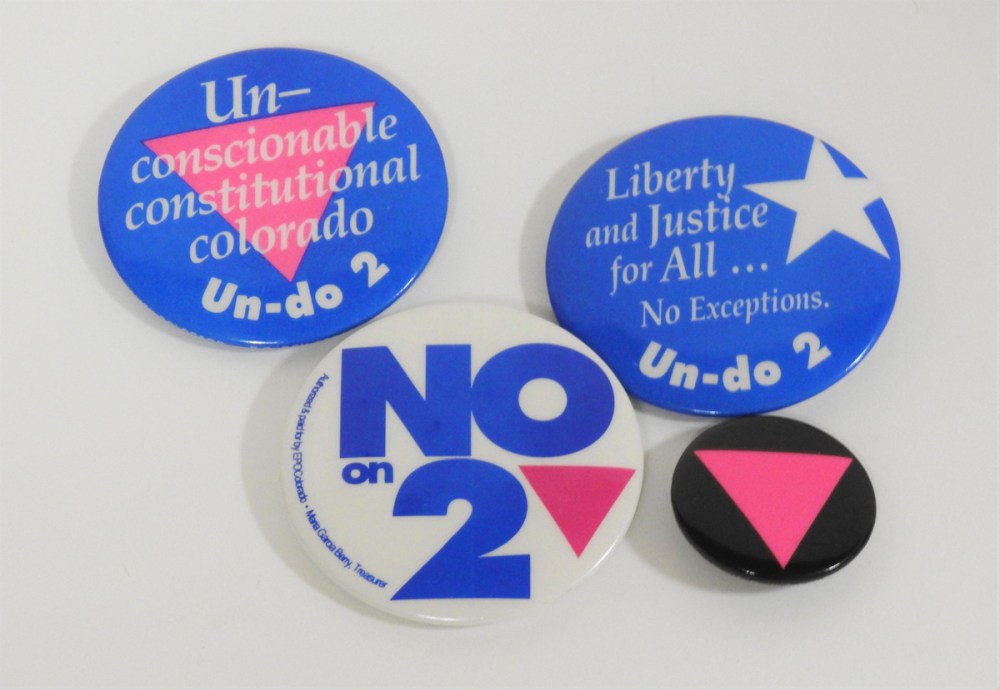 Four buttons with words and symbols opposing Colorado Amendment 2.