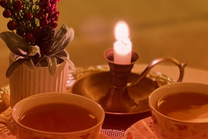 Two teacups on a tray with a lit candle and a small plant arrangement.