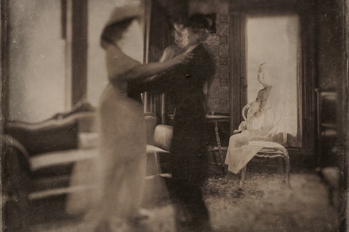 Vintage photo of blurred couple dancing and a seated person in a dress watching.